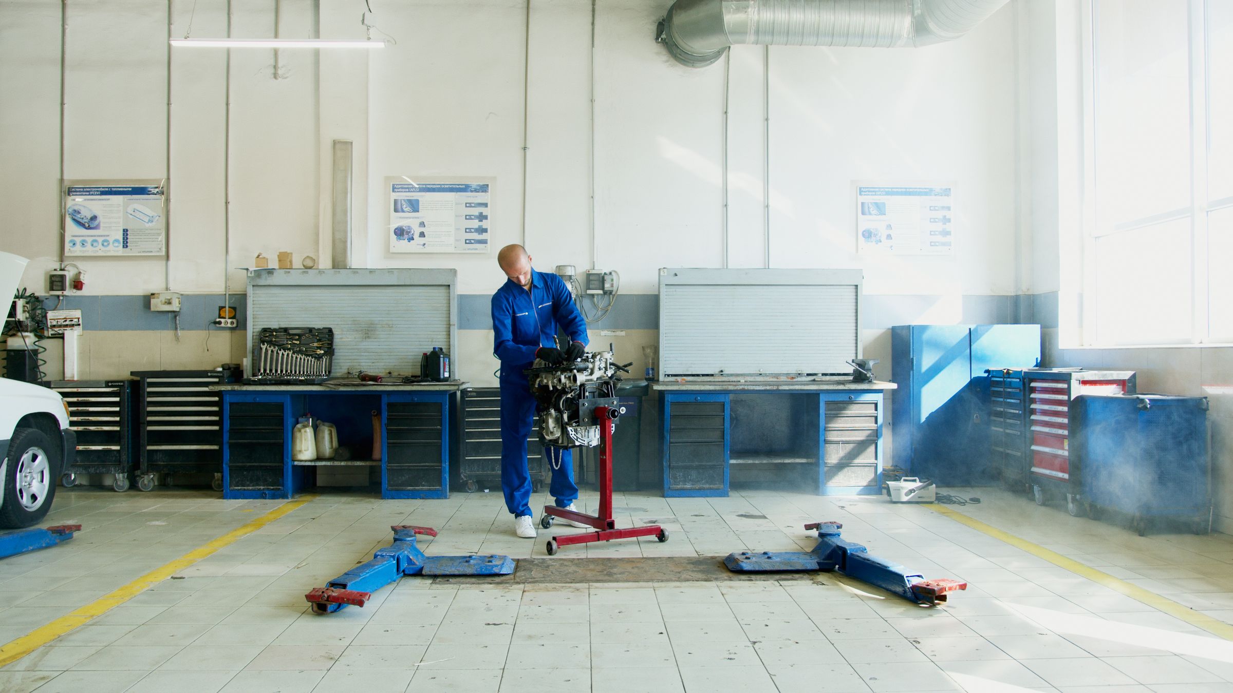 a mechanic working on an engine in a bright shop